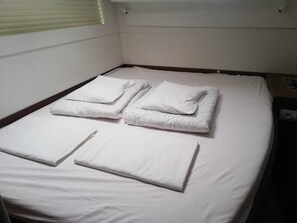 A single bed with white bedding and pillows, a window with blinds, and a wall-mounted air vent. - Dubrovnik Delight: A Sun-Kissed Sailing Experience (Komolac)