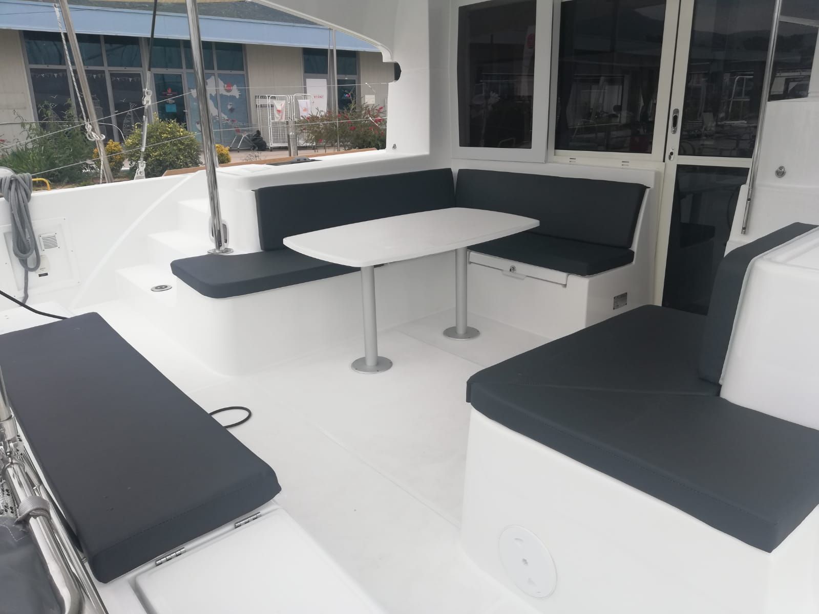 Interior de barco con una mesa blanca, asientos con acolchado negro y ventanas.