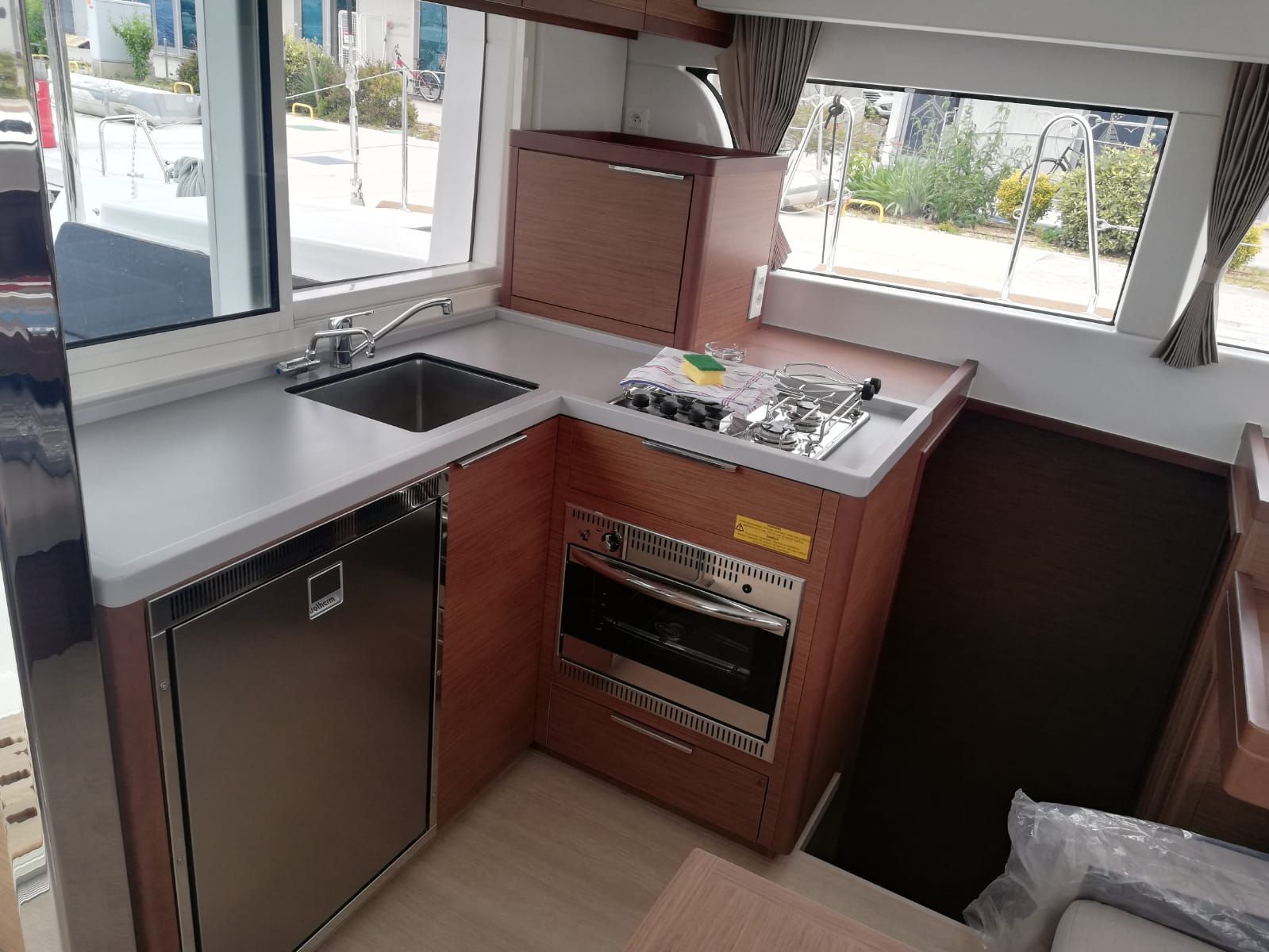 Una cocina compacta con lavamanos, estufa y horno, ventanas amplias y vistas al exterior.