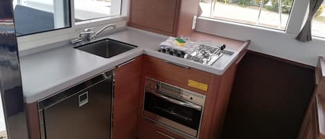 Una cocina compacta con lavamanos, estufa y horno, ventanas amplias y vistas al exterior.