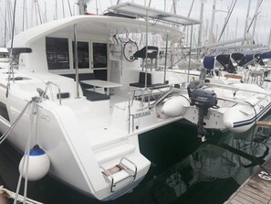 A white yacht docked at a marina with a small enclosed deck area, a table, and a Yamaha outboard motor.