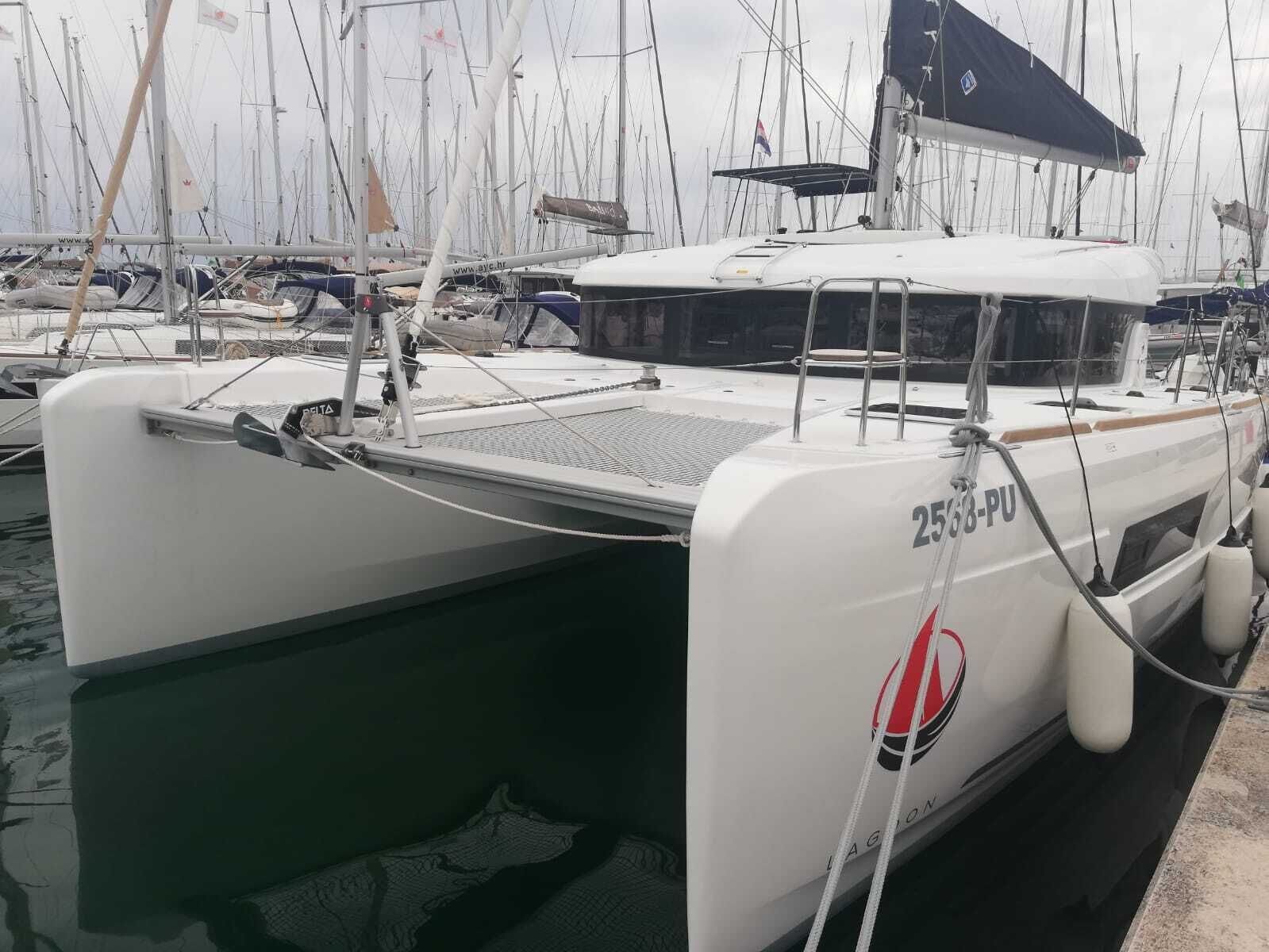 Eine weiße Yacht liegt in einer Marina, umgeben von anderen Booten.