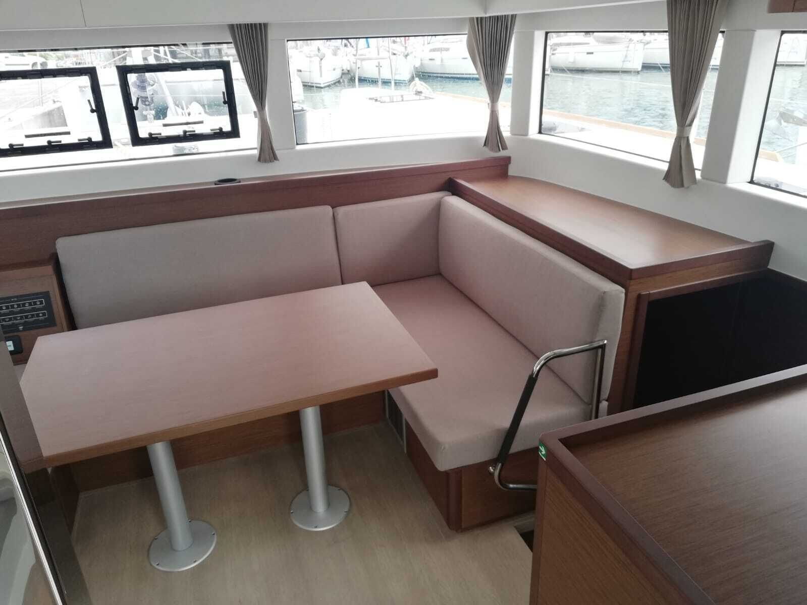 Ein kompaktes Kabinenzimmer mit einer gepolsterten Sitzecke, einem kleinen Tisch und Blick auf den Hafen durch große Fenster.
