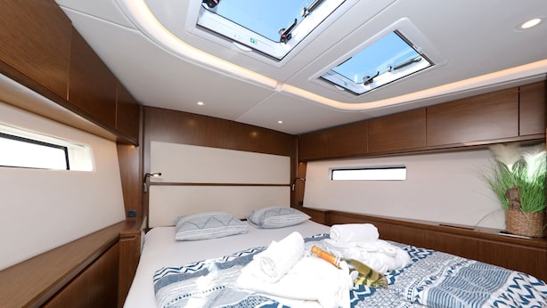 Ein kleines, helles Schlafzimmer mit einem Bett, Dachfenstern und einem kleinen Fenster.