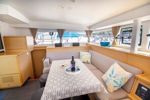 A cozy cabin with a sofa, a table with a bottle and glasses, and a window with curtains. - Sun-Kissed Sailing Adventure in Split, Croatia (Split)