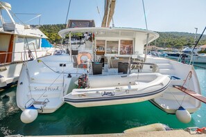 Ein weißes Boot namens 'Second Wind' liegt in einer Marina festgemacht, mit einer Kabine, einer Sitzecke und einem Rettungsring.