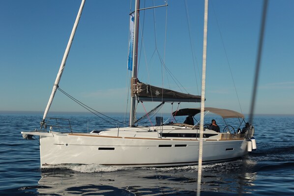 A sailboat with a cabin and a person at the helm.