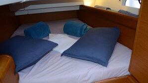 Een klein bed met twee kussens en een opgevouwen deken in een kamer in chaletstijl.