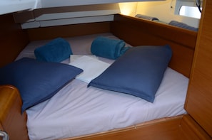 Ein kleines Bett mit zwei Kissen und einer zusammengelegten Decke in einem Blockhauskabinett.