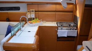 Een kleine kombuis met een spoelbak, kookplaat en een mand met fruit.