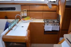 Eine kleine Kombüze mit Spüle, Herd und einer Schale mit Früchten.