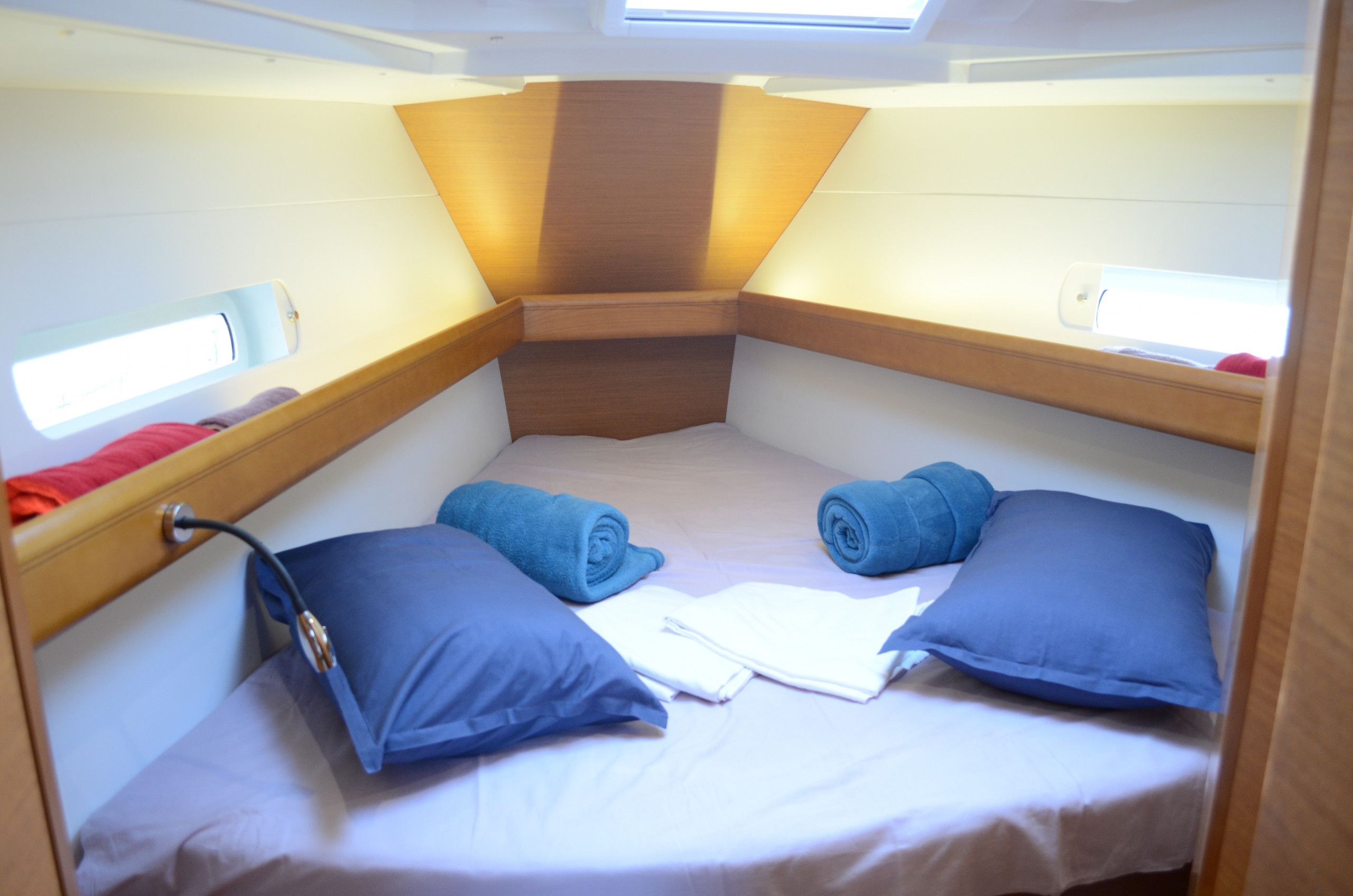 Une petite cabine équipée d’un lit superposé, d’une petite fenêtre et d’une tête de lit avec un luminaire.