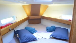 Een knus vakantiehuisje met een stapelbed, een klein raam en een hoofdeinde met een lamp.