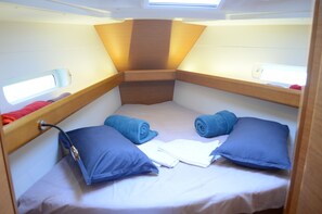 Ein kleines Blockhaus mit Etagenbett, kleinem Fenster und Kopfteil mit Leuchte.