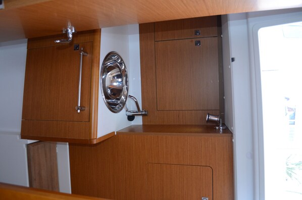 A compact kitchen with wooden cabinets, stainless steel fixtures, and a window.