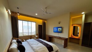 Une chambre d’hôtel équipée d’un lit, d’un bureau, d’une télévision et offrant une vue sur l’extérieur.