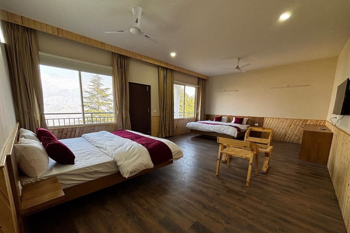 A room with two beds, a wooden chair, a TV, and a balcony with a view.