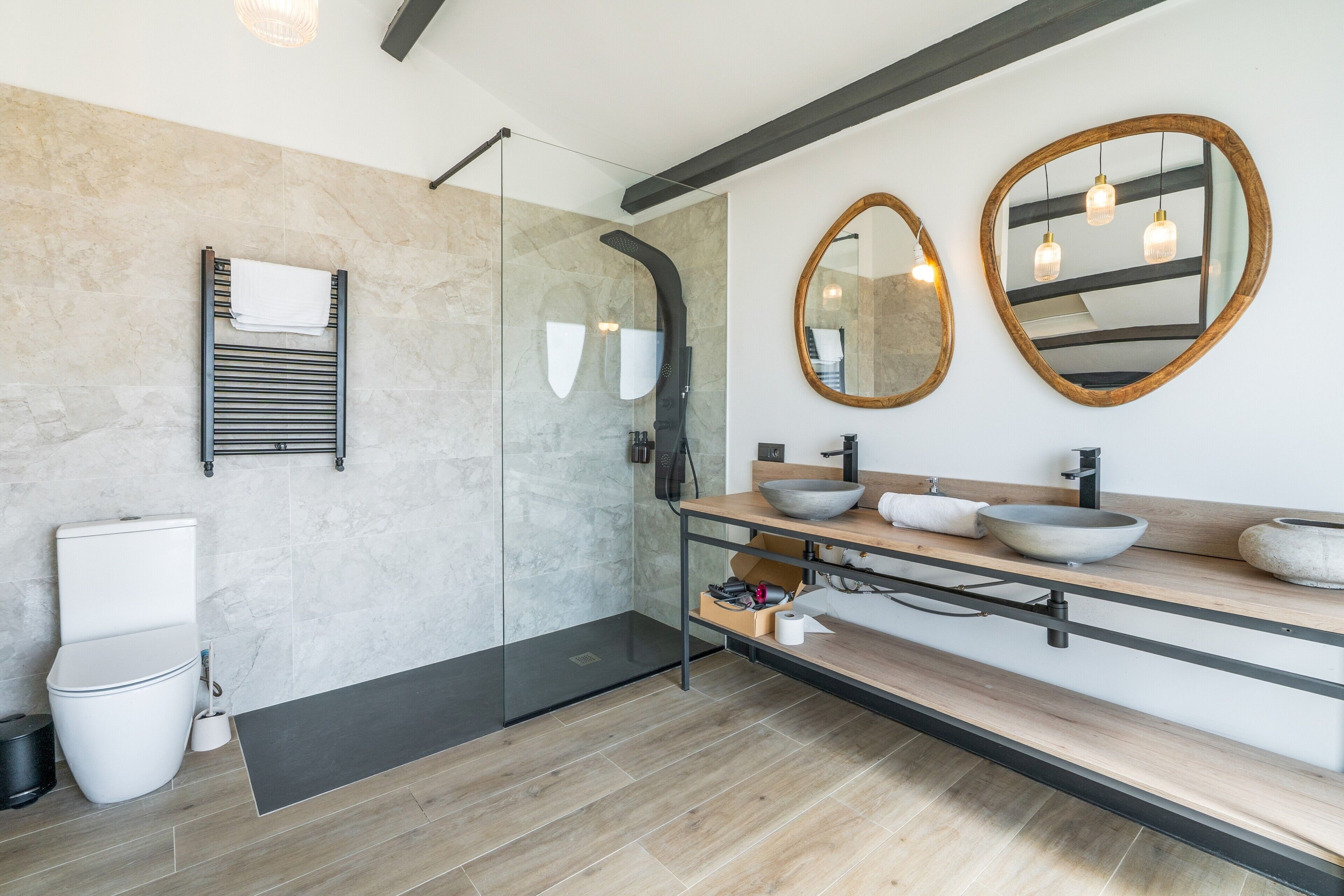 A modern bathroom with a shower, two sinks, and a toilet.