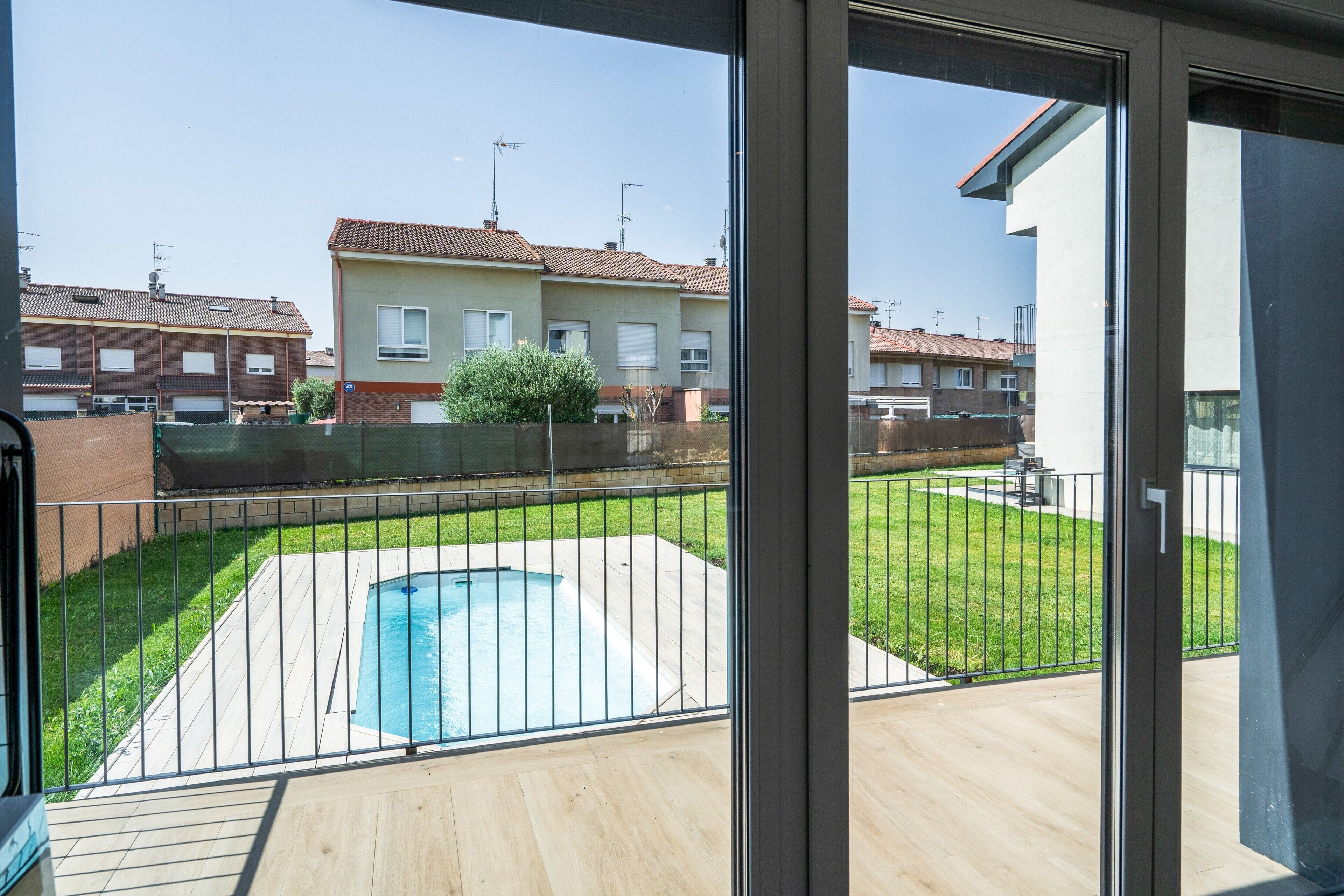 A residential area with a swimming pool, a fenced yard, and neighboring houses.