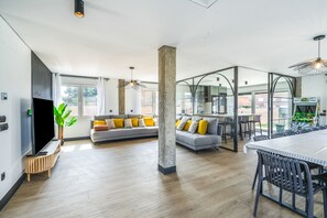 A modern living space with a sofa, dining table, and chairs, a large window, and a plant.