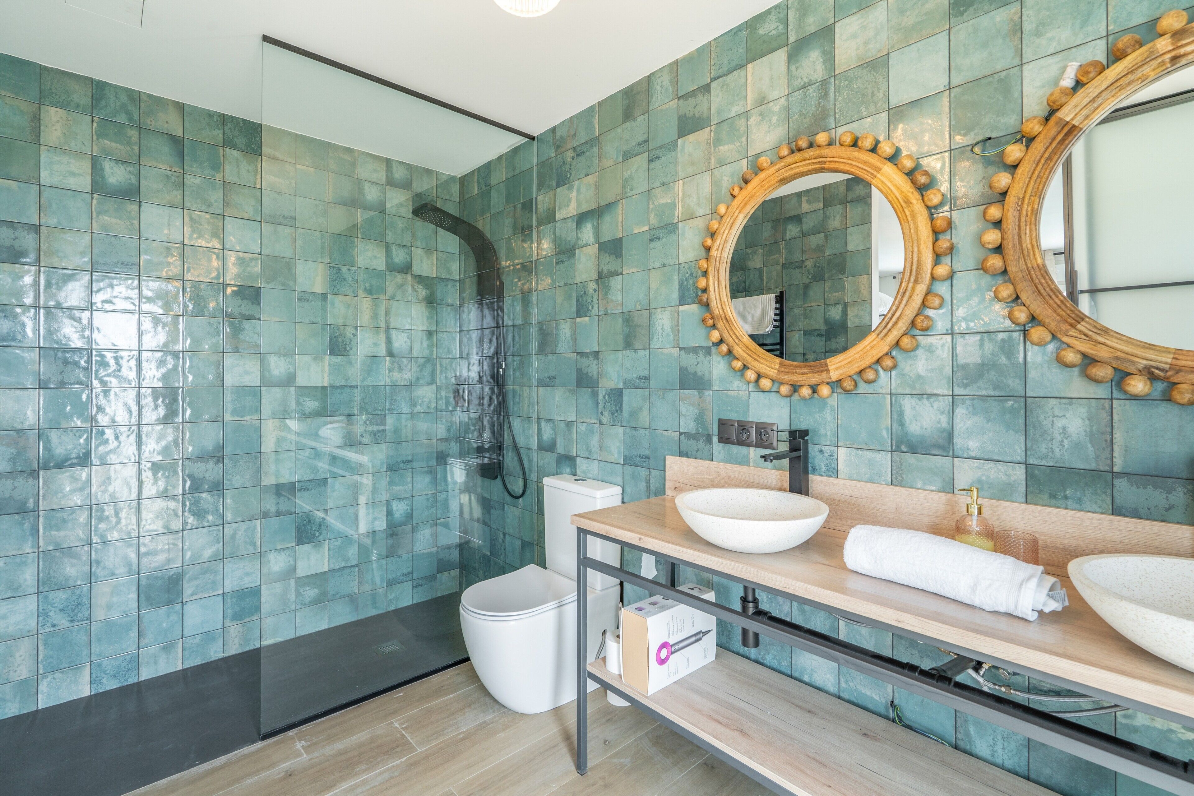Un baño moderno con ducha, dos espejos, lavamanos e inodoro.