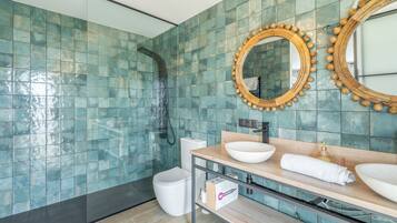 Un baño moderno con ducha, dos espejos, lavamanos e inodoro.