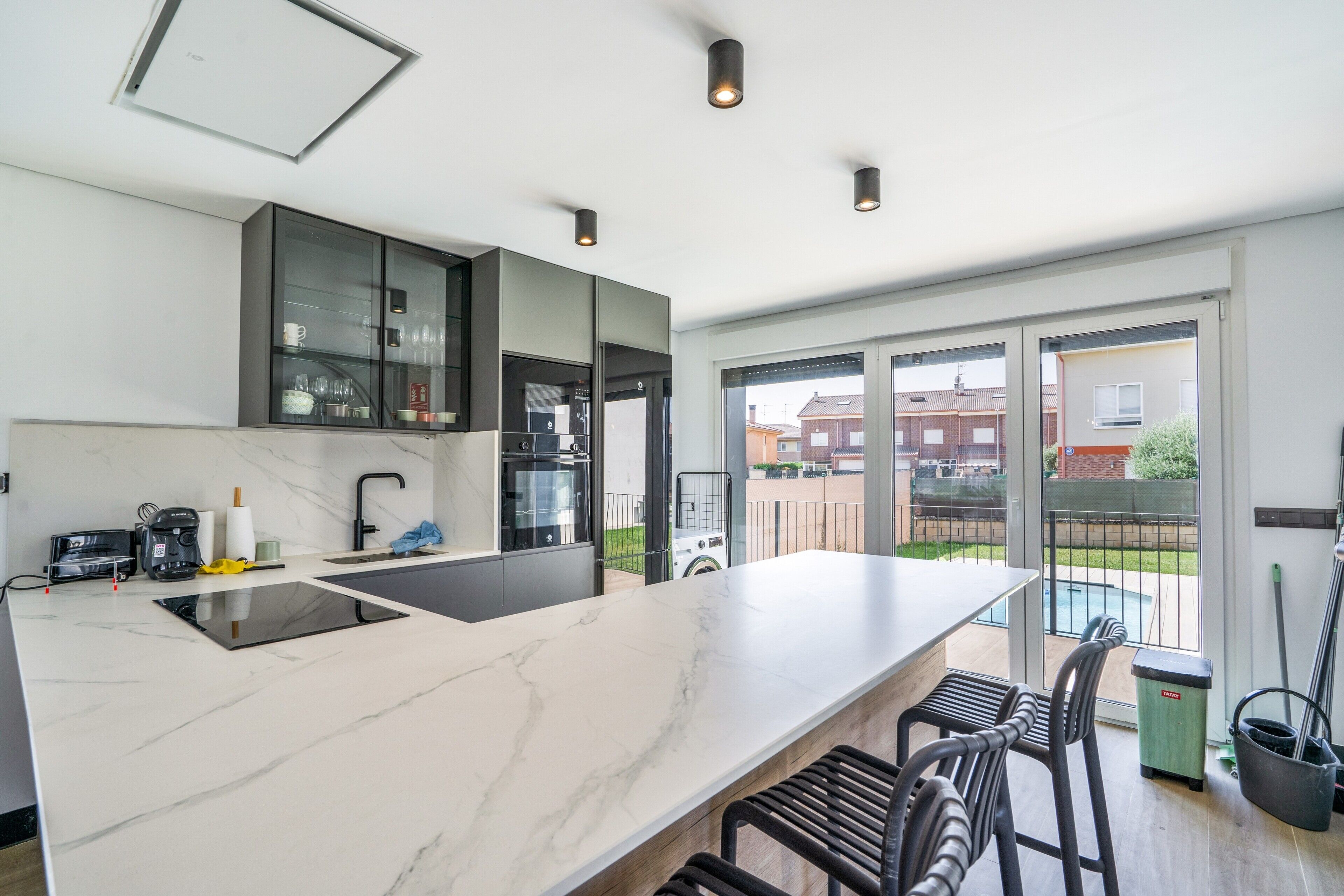 Uma cozinha moderna com uma ilha grande, eletrodomésticos embutidos e vista para o exterior.