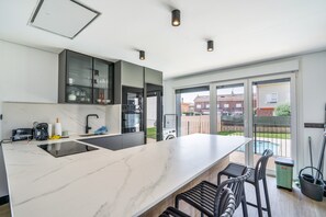 Eine moderne Küche mit einer großen Kochinsel, eingebauten Geräten und Blick ins Freie.