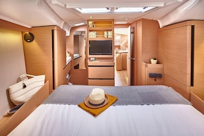 Un interior compacto y bien iluminado con una cama, un televisor y una kitchenette.