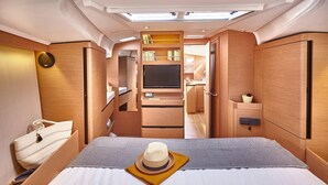Un interno compatto e luminoso con un letto, una TV e angolo cottura.