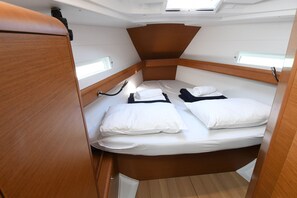 A compact, well-lit cabin with a single bed, a small table, and a wardrobe.