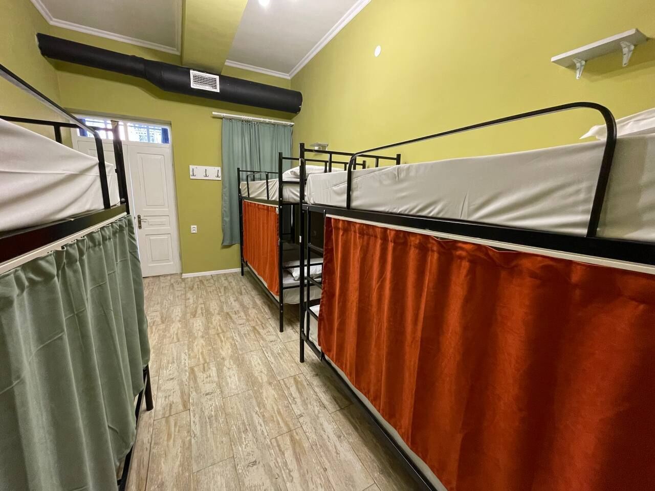 Un dormitorio con literas, un calentador, una puerta y una cortina.