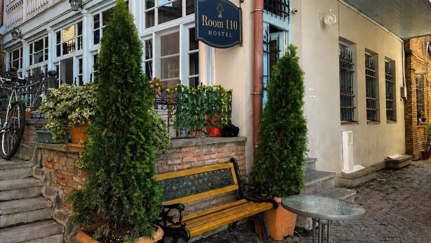 Un bâtiment sur lequel on peut lire l’inscription « Auberge de jeunesse, chambre 110 ». Il y a un banc et une table à l’extérieur.