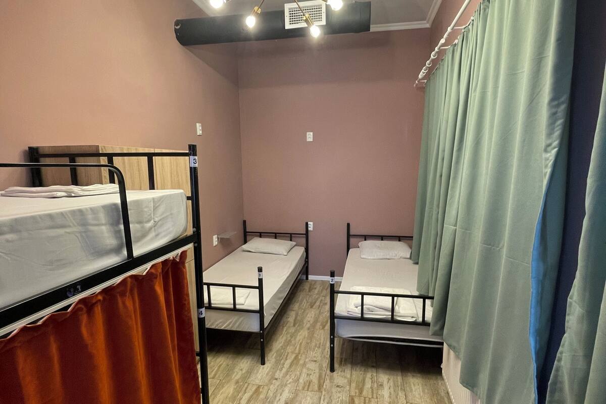 A room with bunk beds, a ceiling fan, and a radiator.
