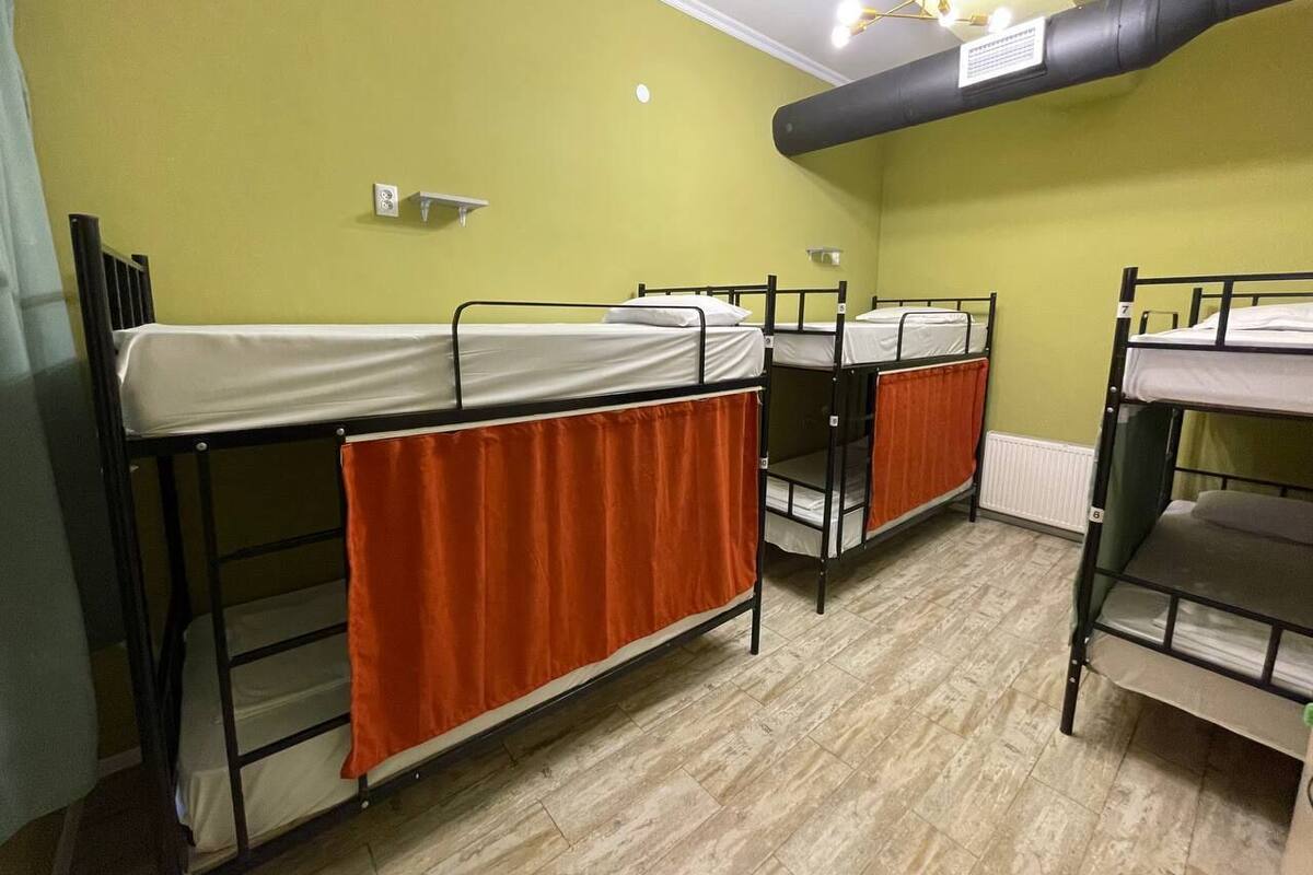 A dormitory room with bunk beds, a radiator, and a light fixture.