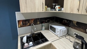 Une cuisine compacte équipée d’un évier, d’un four à micro-ondes et d’une bouilloire.