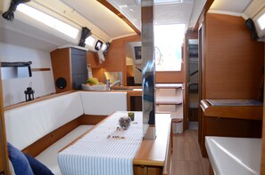 Un interior de barco compacto con comedor, pequeña cocina y zona de estar.
