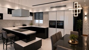 Uma cozinha moderna com ilha central, eletrodomésticos embutidos e um espaço de jantar com mesa e cadeiras.