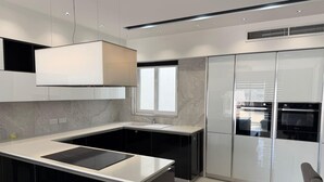 Uma cozinha moderna com ilha central, eletrodomésticos embutidos e uma janela grande.