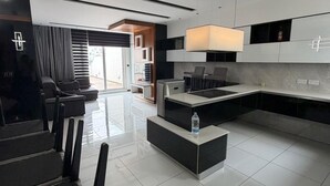 Uma cozinha moderna com ilha central, armários em preto e branco e uma grande janela.