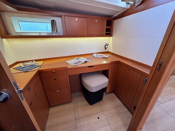 A compact kitchenette with wooden cabinetry, a countertop, and a small stool.