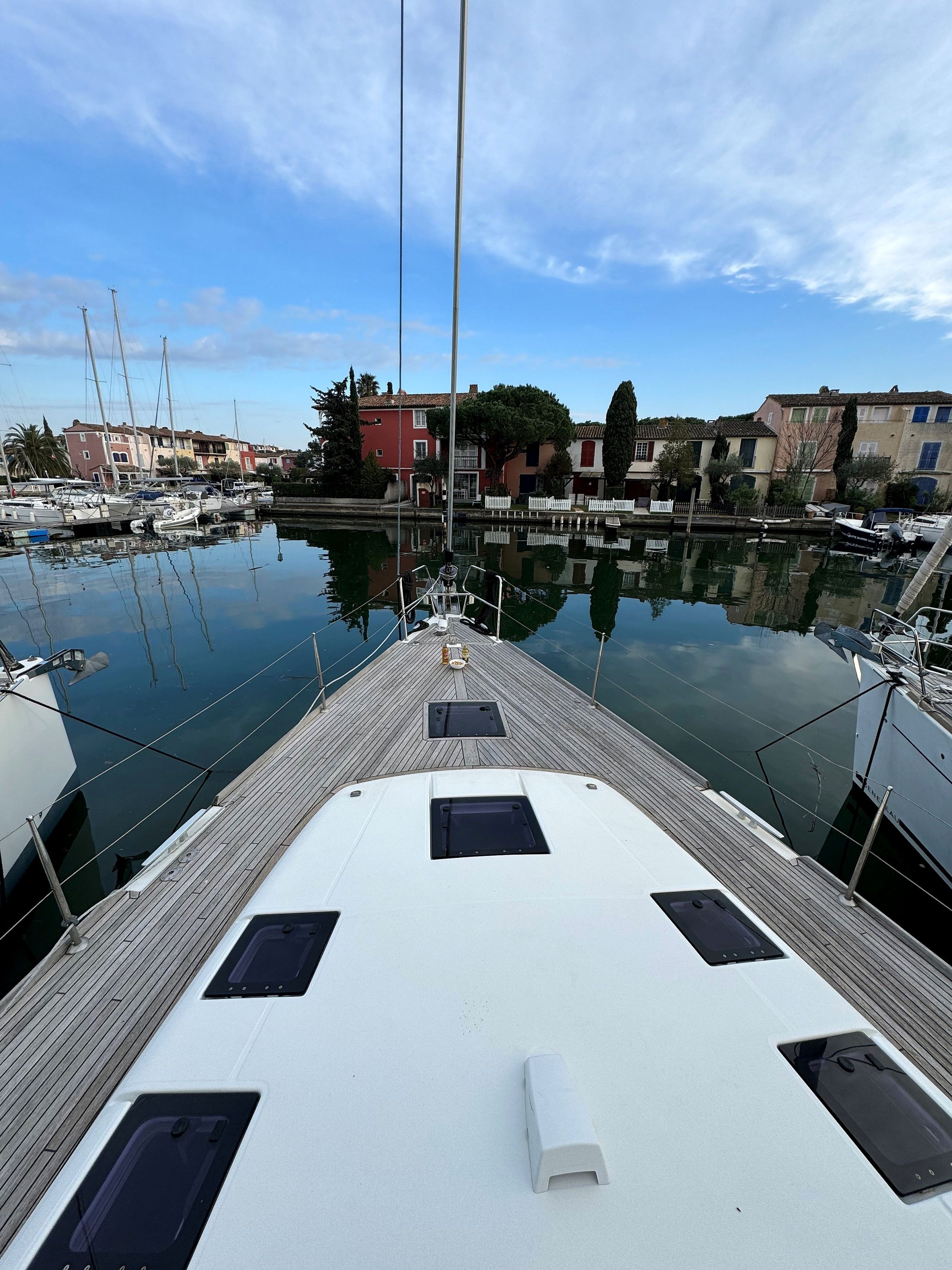 A marina with boats docked, a wooden deck, and buildings in the background.