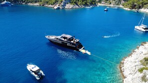 A large yacht anchored in a clear blue bay with rocky shores and other boats nearby. - Sun-Kissed Sailing Adventure in Split, Croatia (Split)