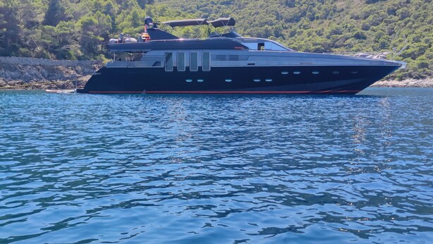 A large, dark-colored yacht on calm water with a forested hillside in the background. - Sun-Kissed Sailing Adventure in Split, Croatia (Split)