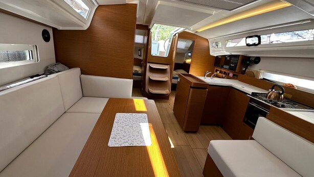 A compact boat interior with a seating area, a small kitchenette, and a window providing natural light.