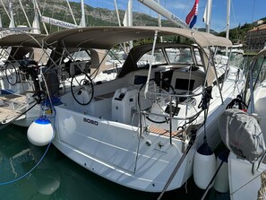 A sailboat docked at a marina with a cabin, steering wheel, and various navigational equipment.