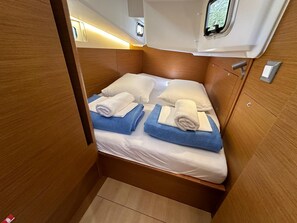 A compact, well-lit cabin with a single bed, neatly folded towels, and a small window. - Dubrovnik Delight: A Sun-Kissed Sailing Experience (Komolac)