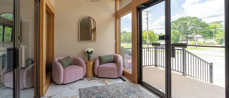 A modern interior with a large glass door leading to an outdoor area, a marble floor, and a small round table with a vase.