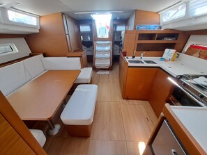 A compact kitchen with a sink, stove, and storage cabinets. - Sun-Kissed Sailing Adventure in Split, Croatia (Kaštel Gomilica)