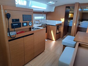 A compact kitchen with a refrigerator, stove, and a small sink. - Sun-Kissed Sailing Adventure in Split, Croatia (Kaštel Gomilica)